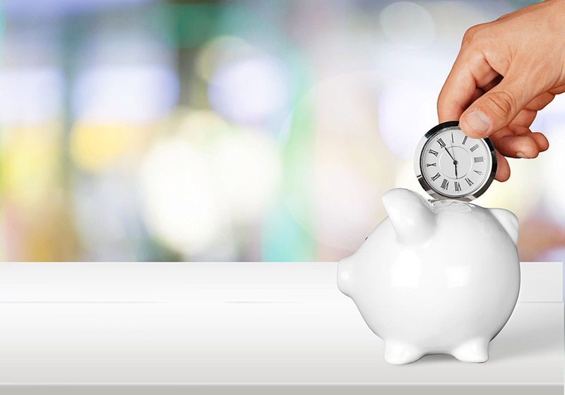 hand putting small clock into white piggy bank